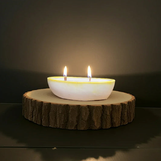 Handgemachte Kerze mit zwei Flammen in Schale auf Holzunterlage, stimmungsvolles Licht