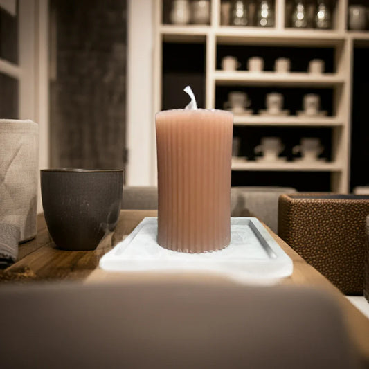 Handgemachte, geriffelte Stumpenkerze auf Tablett im gemütlichen Wohnzimmer-Ambiente