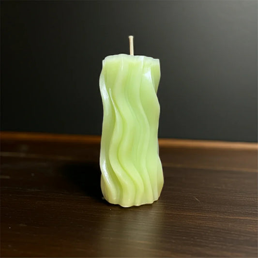 Handgemachte grüne Kerze mit Wellenmuster auf dunkler Holzoberfläche