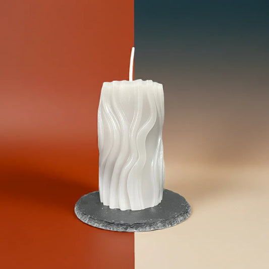 Weiße handgemachte Kerze mit Wellenmuster auf Steinuntersetzer, stimmungsvolle Dekoration