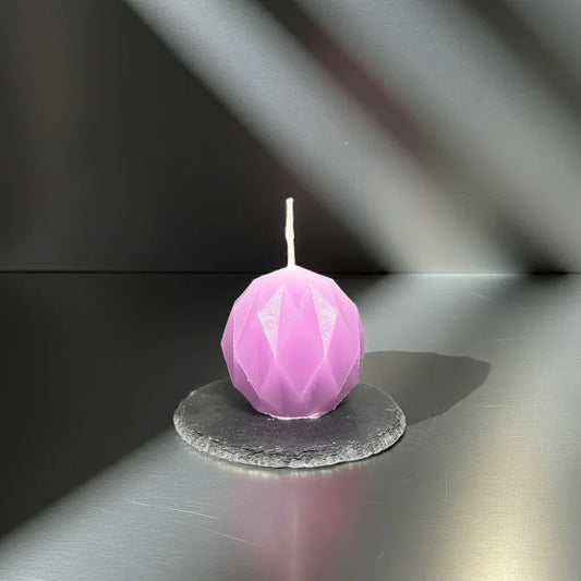 Handgemachte lila Kerze im geometrischen Design auf schwarzer Schieferplatte, moderne Deko