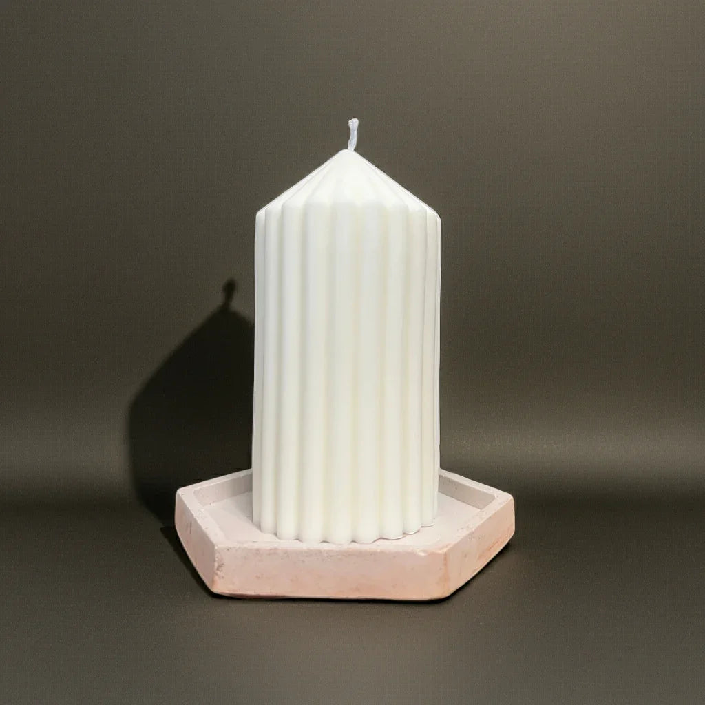 Weiße geriffelte Kerze auf sechseckiger Kerzenplatte vor dunklem Hintergrund