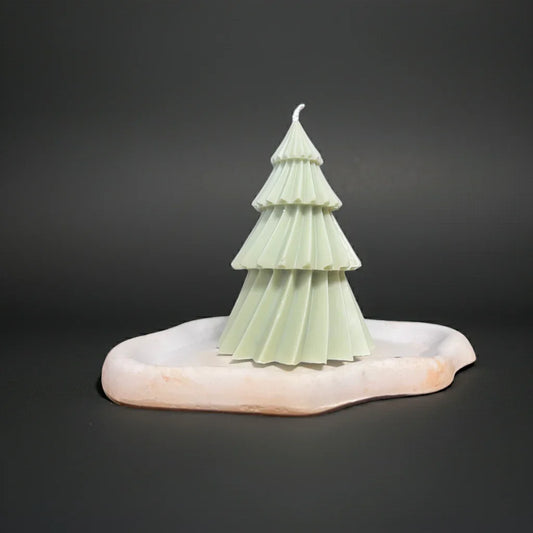 Handgemachte Baumkerze in Tannenform auf weißem Kerzenteller, minimalistisches Design