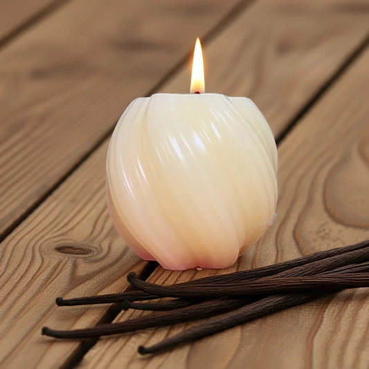 Handgemachte Kugelkerze brennend auf Holztisch, daneben Vanilleschoten, entspannende Stimmung