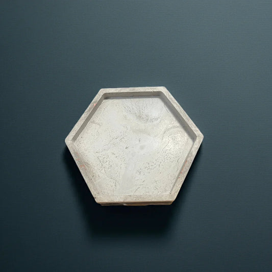 Sechseckige Beton-Kerzenunterlage auf dunklem Hintergrund, minimalistisch und handgemacht