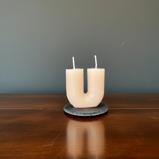 Handgemachte U-förmige Kerze in Cremefarbe auf Holzuntergrund, minimalistische Deko