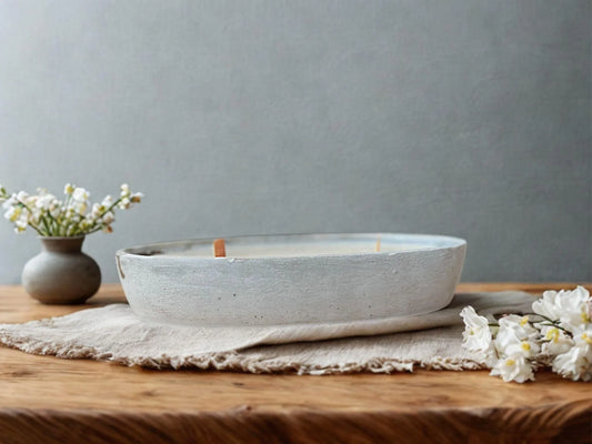 Handgemachte Kerze in Betonschale auf Holztisch mit Blumen und natürlicher Deko