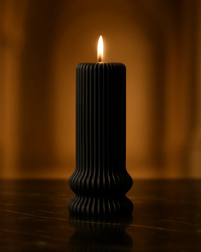 Schwarze geriffelte Kerze brennt auf Tisch, stimmungsvolles, warmes Licht