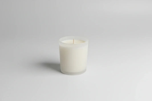 Weiße handgemachte Kerze im Glas auf hellem Hintergrund, minimalistisch und nachhaltig