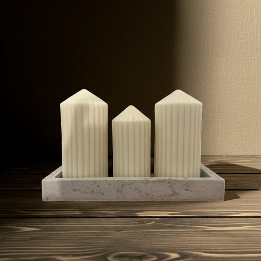 Drei handgemachte, weiße Stabkerzen mit Rillenmuster in rechteckiger Schale auf Holz.