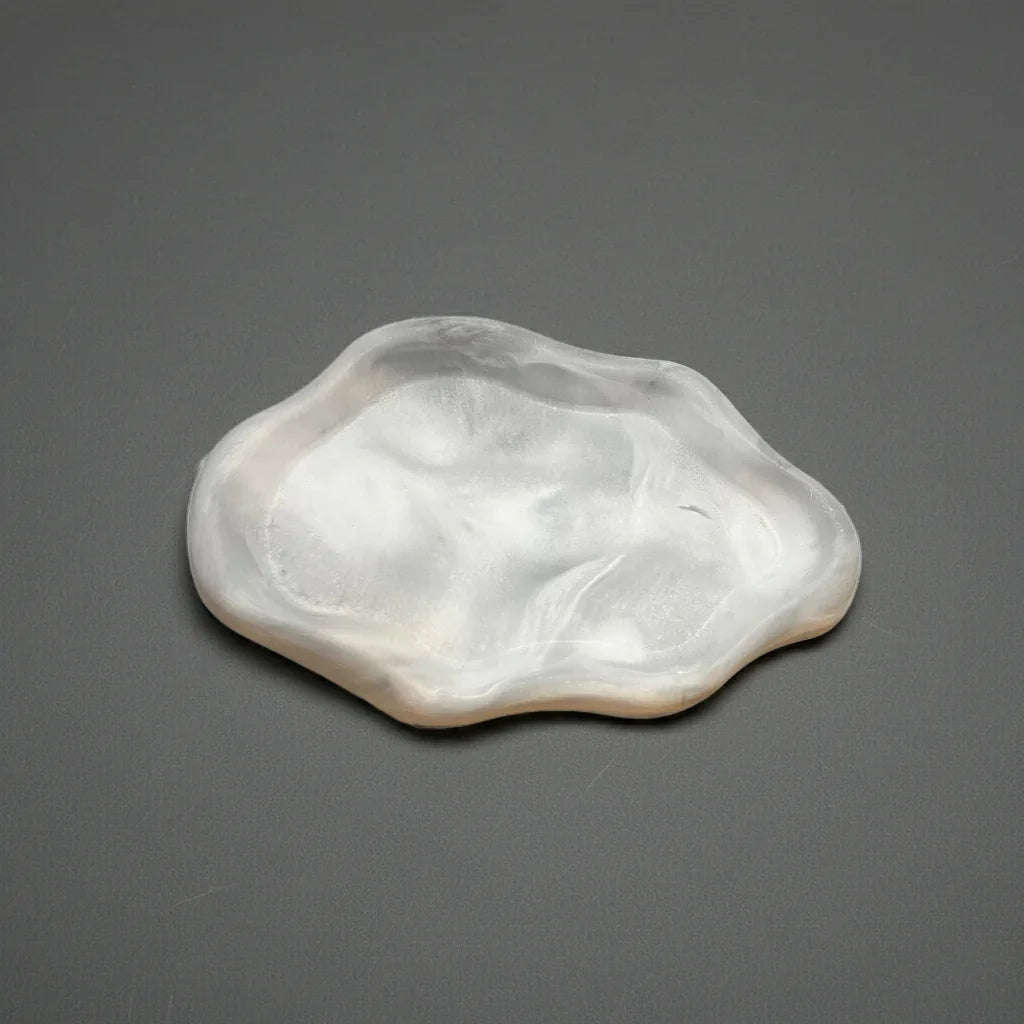 Handgemachte, weiße Kerzenschale aus Resin mit organischer Form auf grauem Hintergrund