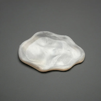 Handgemachte, weiße Kerzenschale aus Resin mit organischer Form auf grauem Hintergrund