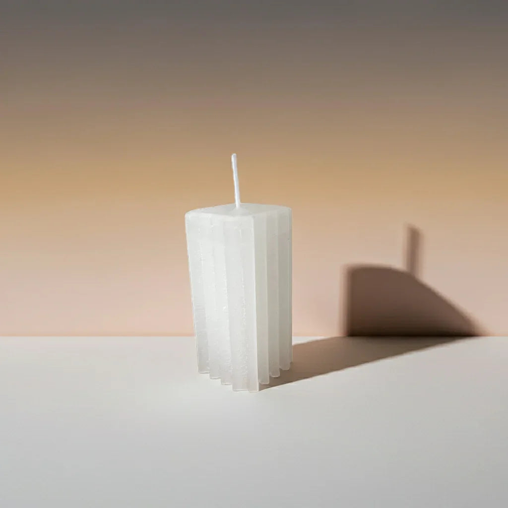 Weiße, handgemachte Stumpenkerze mit geometrischem Design auf hellem Untergrund