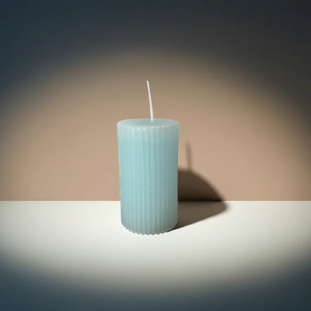 Handgemachte geriffelte Kerze in Hellblau auf hellem Tisch, modernes Ambiente