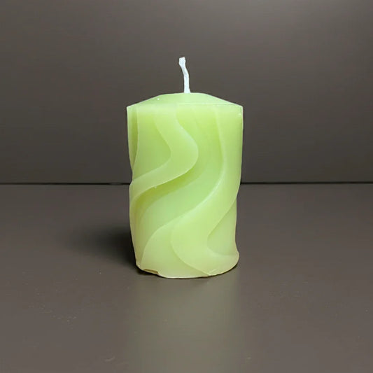 Handgemachte grüne Kerze mit Wellenmuster auf neutralem Hintergrund, stimmungsvolles Licht