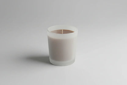 Handgemachte Duftkerze im matten Glas, minimalistisch auf hellem Hintergrund