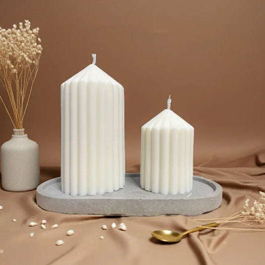 Zwei handgemachte geriffelte Stumpenkerzen in Creme auf Tablett, dekorativ arrangiert