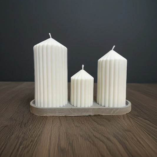 Drei handgemachte weiße Kerzen mit Rillenstruktur auf Holzuntergrund, stilvoll arrangiert