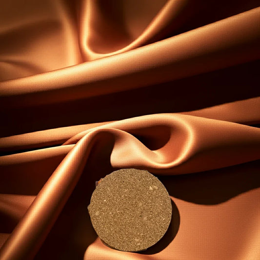 Handgemachte Kerze rund auf goldener, glänzender Stoffoberfläche, nachhaltiges Design