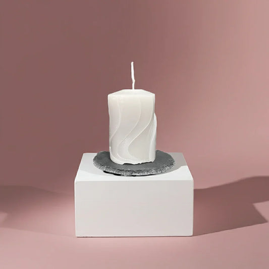 Handgemachte weiße Kerze mit wellenförmigem Muster auf Schieferuntersetzer, dekorativ