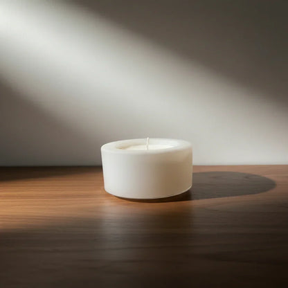 Handgemachte weiße Kerze auf Holzoberfläche im Sonnenlicht, minimalistische Deko