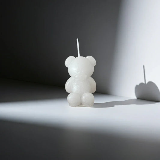 Handgemachte Kerze in Bärenform, weiß, dekorativ beleuchtet auf neutralem Hintergrund