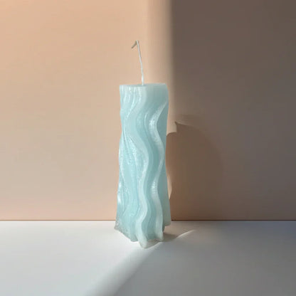 Handgemachte Wellenkerze in Pastellblau auf minimalistischem Hintergrund, dekorative Kerze