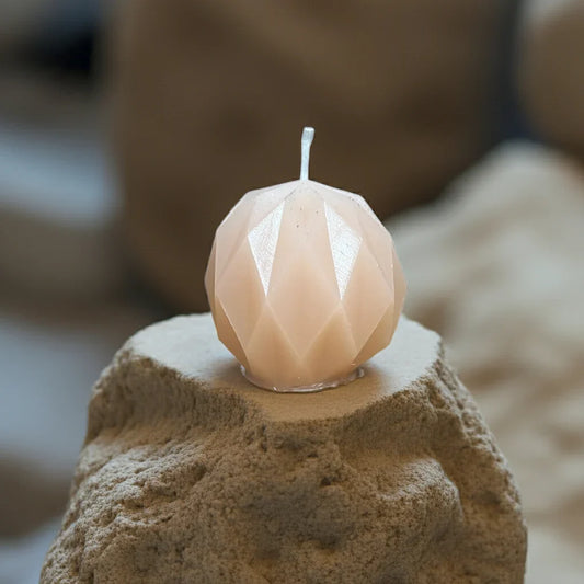 Handgemachte geometrische Kerze in Beige auf sandigem Stein, stimmungsvolles Licht