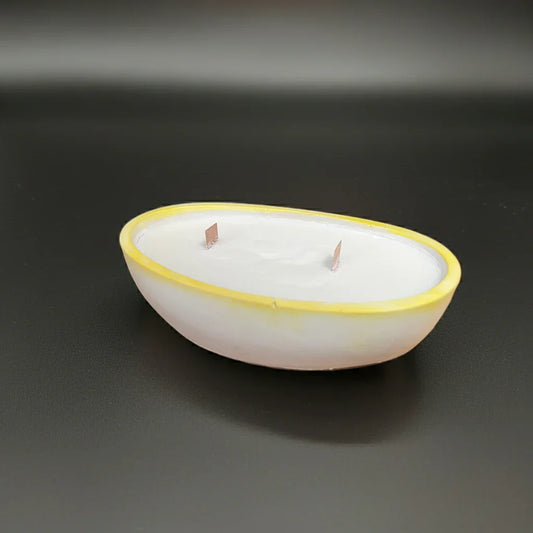 Handgemachte ovale Kerze mit gelbem Rand und zwei Dochten auf schwarzem Hintergrund