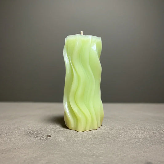 Handgemachte grüne Kerze mit gewelltem Design auf grauem Hintergrund