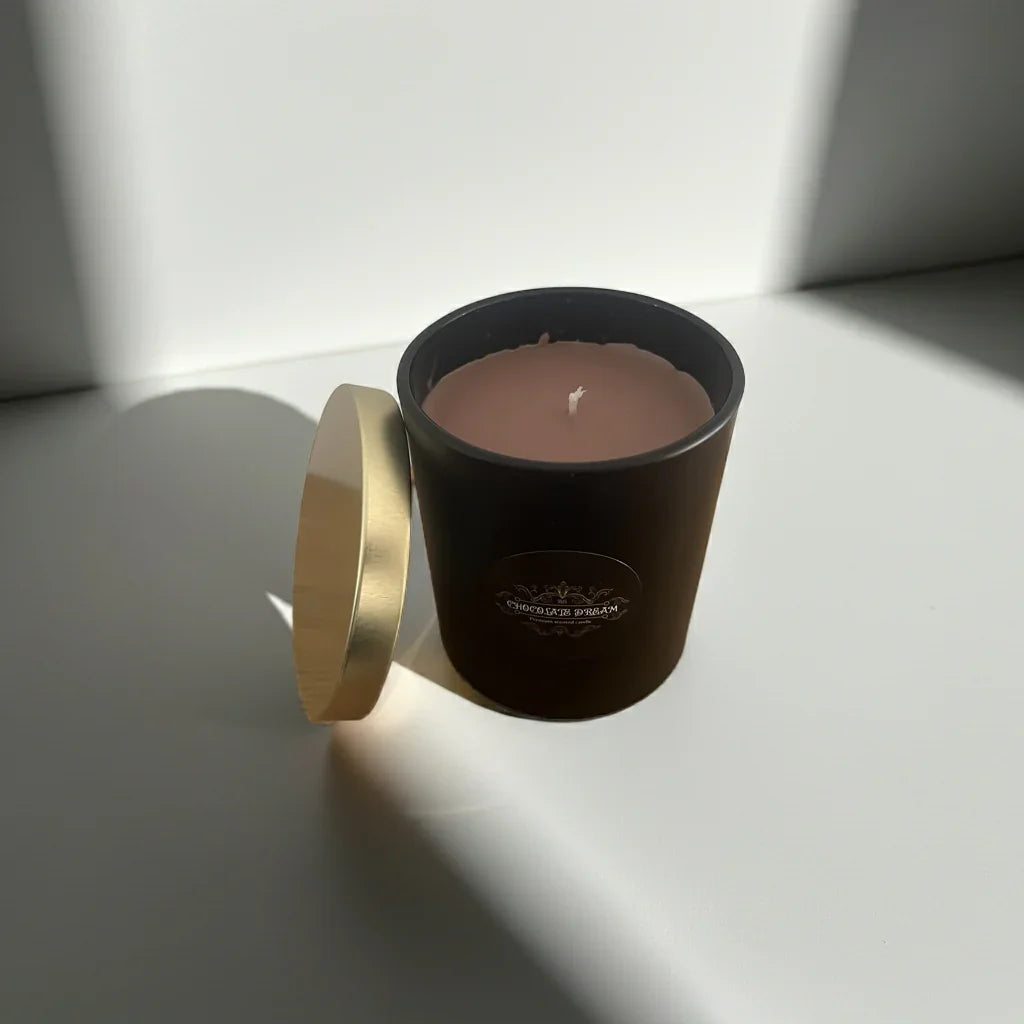 Handgemachte Duftkerze im braunen Glas mit goldenem Deckel auf weißem Hintergrund