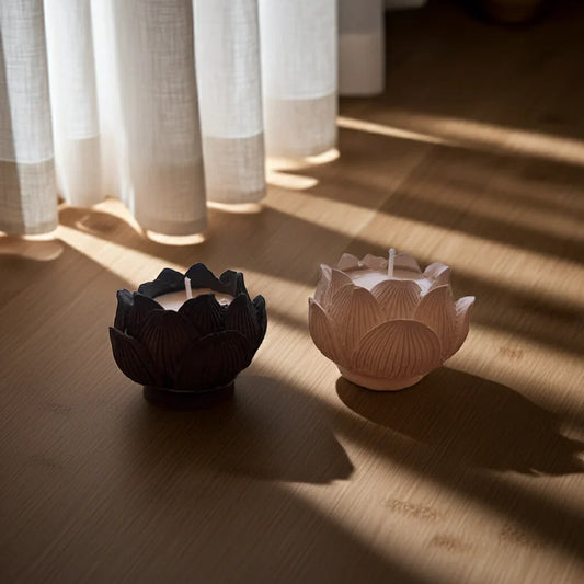 Zwei handgemachte Lotus Kerzen aus Wachs auf hellem Holzboden vor Vorhang, Sonnenlicht