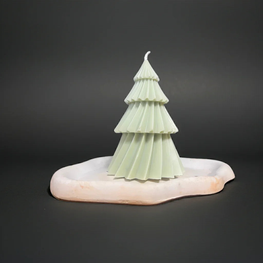 Handgemachte Baumkerze in Tannenform auf weißem Kerzenteller, minimalistisches Design