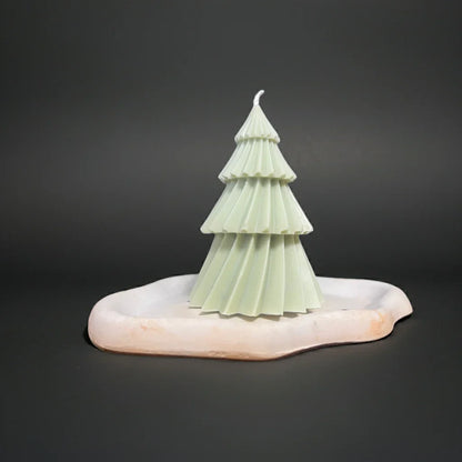Handgemachte Baumkerze in Tannenform auf weißem Kerzenteller, minimalistisches Design