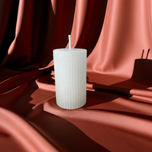Weiße, handgemachte Stumpenkerze auf rotbraunem Stoff, nachhaltige Deko