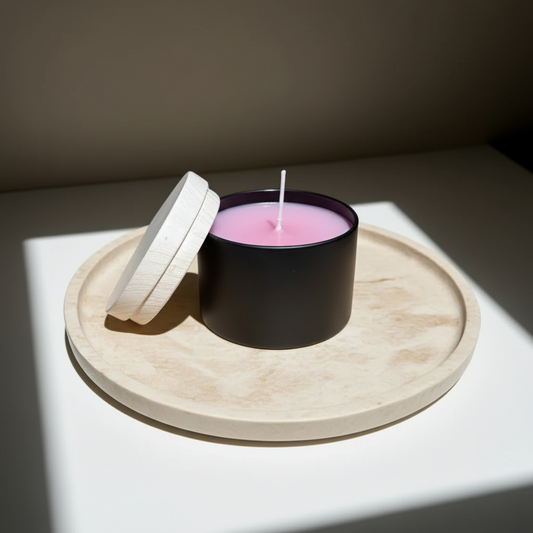 Handgemachte Duftkerze in schwarzer Dose mit Holzdeckel, rosa Wachs auf Holztablett