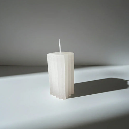 Handgemachte, weiße Stabkerze mit geometrischem Design auf neutralem Hintergrund