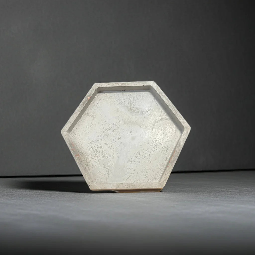 Sechseckige Kerzenschale aus hellem Beton, minimalistisch auf grauem Hintergrund