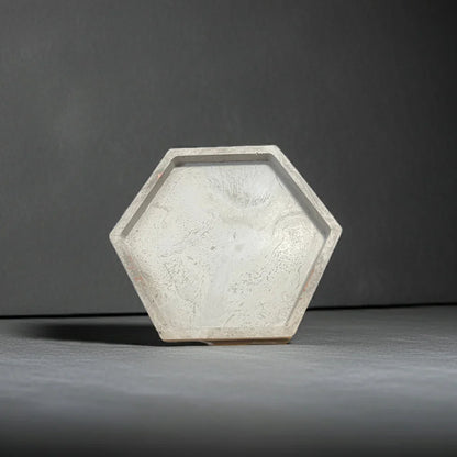 Sechseckige Kerzenschale aus hellem Beton, minimalistisch auf grauem Hintergrund