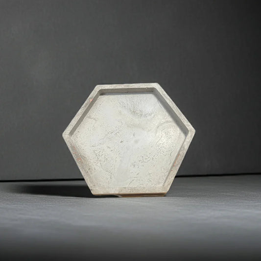 Sechseckige Kerzenschale aus hellem Beton, minimalistisch auf grauem Hintergrund